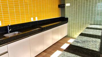A modern kitchen with a black countertop, yellow and green tiled backsplash, and a wooden floor.