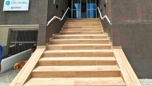 A set of wooden stairs leading to a building entrance with a sign above reading "Cúpico Gardenia."