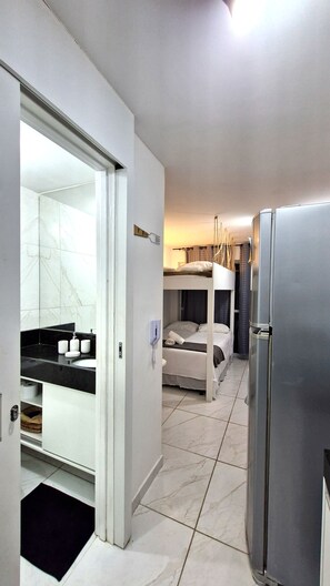 A modern hotel room with a kitchen area, a built-in wardrobe, and a balcony with a view. - Flat no Cupe Garden - Porto de Galinhas (Ipojuca)