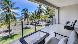 Et moderne værelse med balkon med udsigt over en strand med palmer og havet.