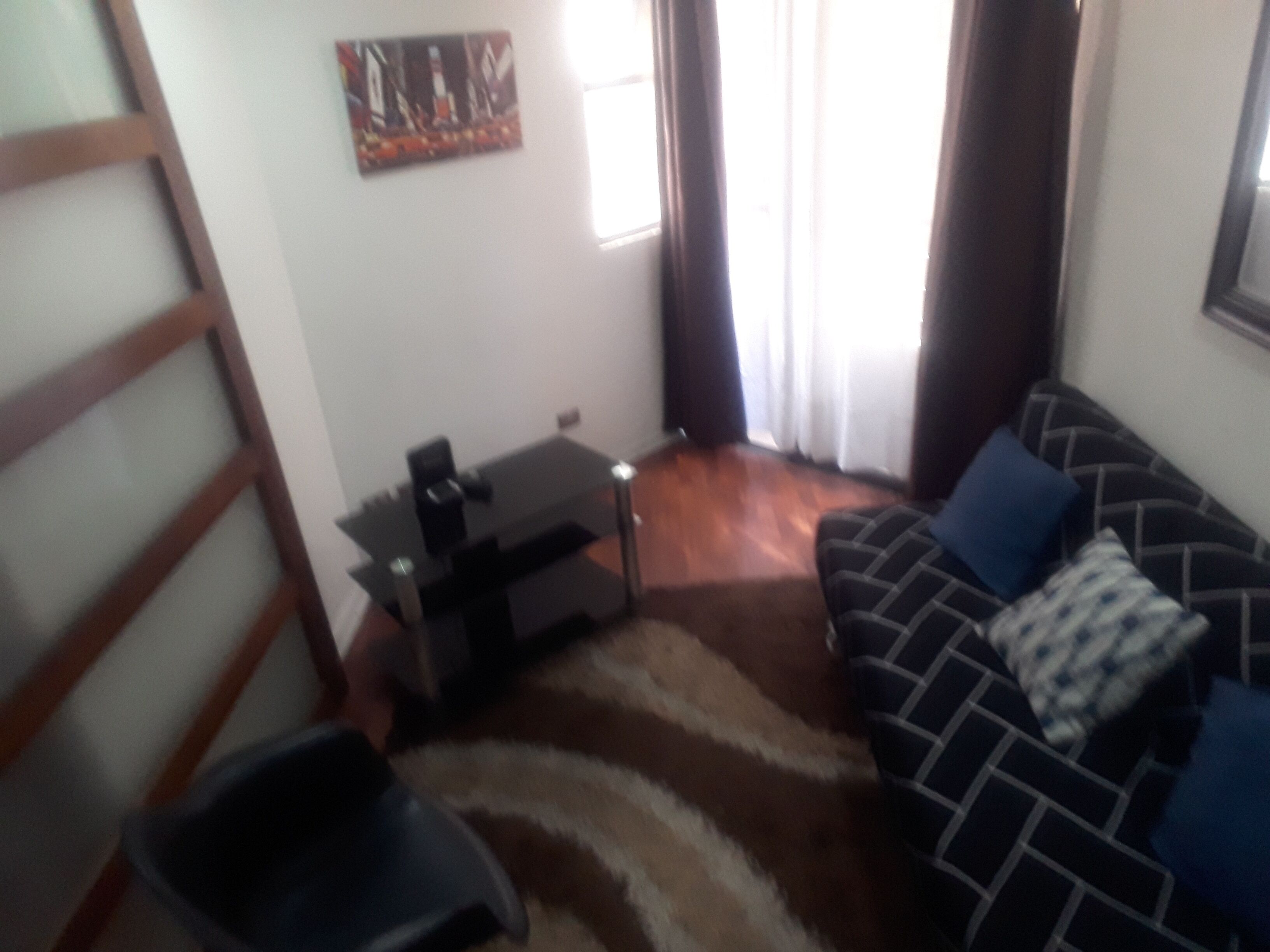 A living room with a sofa, a small table, a chair, and a rug.