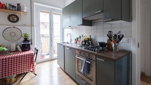 A kitchen with a stove, oven, and a dining table with a checkered tablecloth. - Trastevere Bright Enchanting Apartment (Roma)
