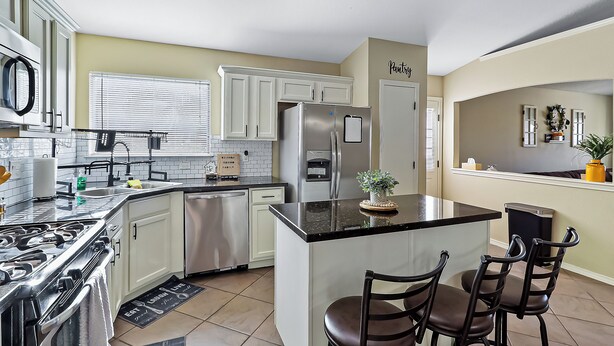 A modern kitchen with white cabinets, stainless steel appliances, and a central island with bar stools. - Cozy Farm House Home Located Near Main Freeways SUPER HOST on other platforms  (El Paso)
