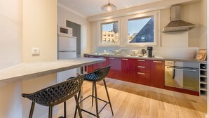 Una cuina moderna amb una illa central, armaris vermells i una campana extractora d'acer inoxidable.