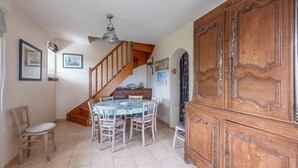 Un comedor con una escalera de madera, una araña y un amplio aparador de madera.