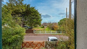 Zona residencial con entrada protegida por una reja, un coche aparcado y casas al fondo.