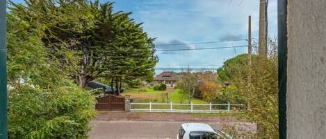A residential area with a gated driveway, a parked car, and houses in the background.