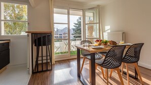 A modern kitchen with a dining area, large windows, and a view of the outdoors. - Place Cosy - Charmant appt pour 4 (Courcouronnes)