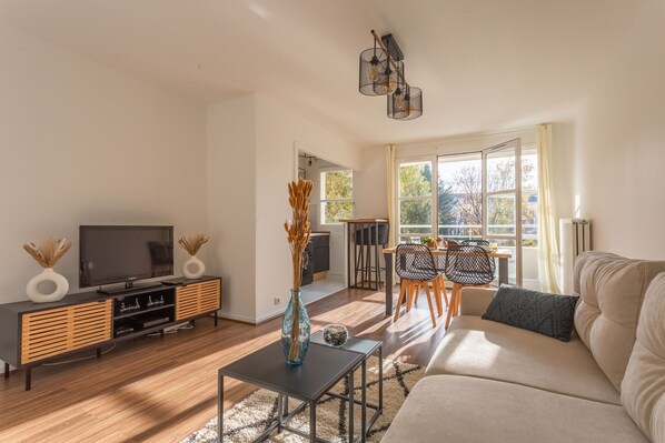 Ein modernes Wohnzimmer mit Sofa, Fernseher und Essbereich.