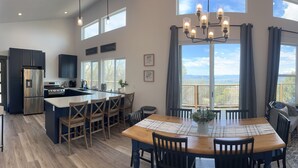 A spacious kitchen with a central island, dining area with a wooden table and chairs, and a living room with a sofa and fireplace. - Your Hideaway Surrounded by the Breathtaking Beauty of Utah's Natural Landscape (Fairview)