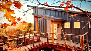 A modern house with a wooden deck and a glass enclosure. - Your Hideaway Surrounded by the Breathtaking Beauty of Utah's Natural Landscape (Fairview)