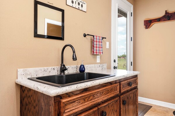 A kitchen with a double sink, wooden cabinets, a marble countertop, a mirror, and a towel rack.