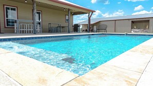 A swimming pool with a covered patio area, outdoor furniture, and a building with large windows and a garage. - Countryside Texas Sanctuary Enjoy Sunrises & Sunsets, Grill, Firepit & Longhorns (Pattison)