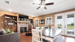 A spacious living area with a fireplace, dining table, and comfortable seating. - Countryside Texas Sanctuary Enjoy Sunrises & Sunsets, Grill, Firepit & Longhorns (Pattison)