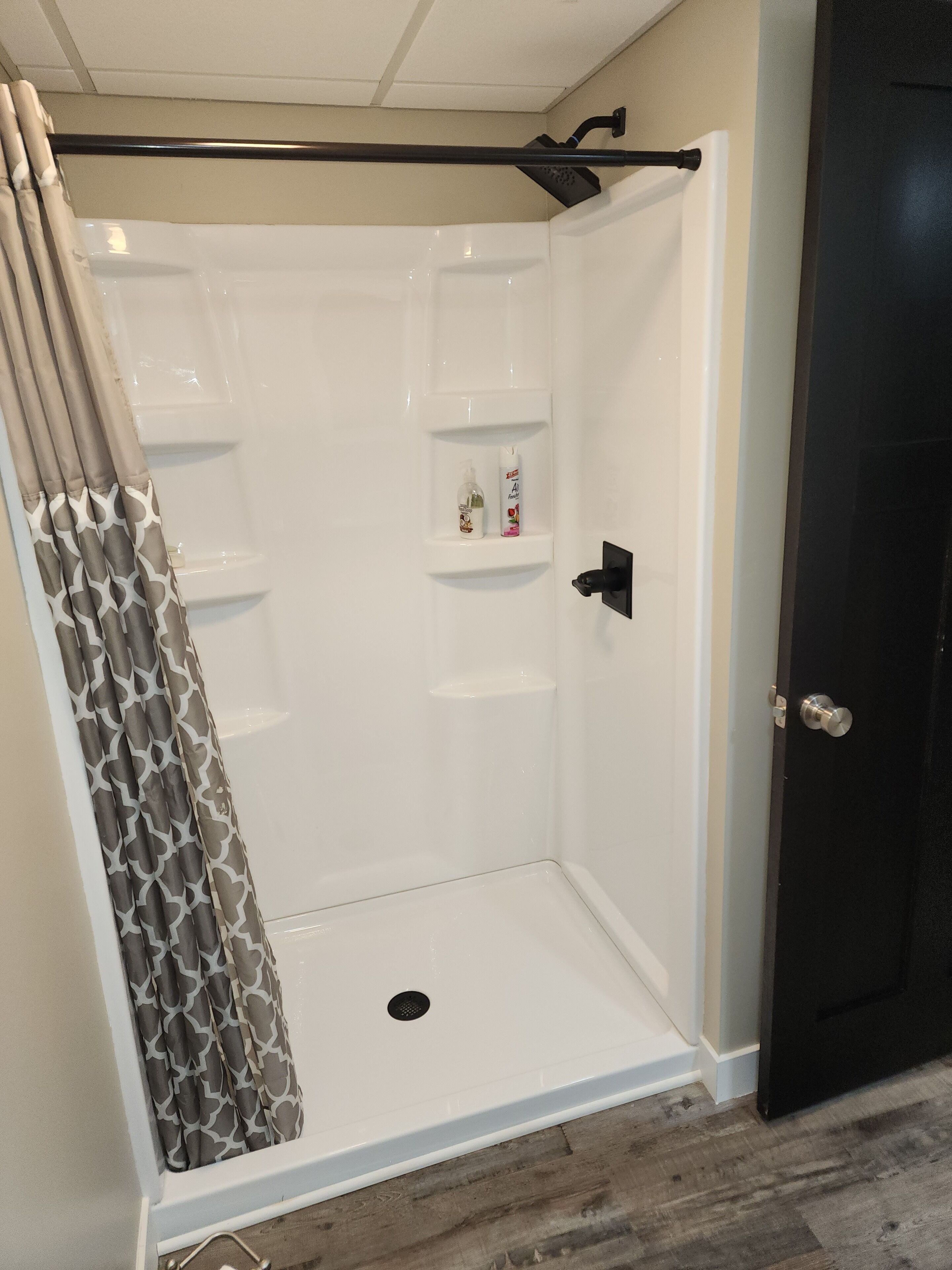 A walk-in shower with a showerhead, a hand dryer, and a shelf with toiletries.