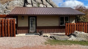 A cabin with a metal roof, wooden exterior, and a gravel driveway. - Paradise Land Cabin A (Custer)