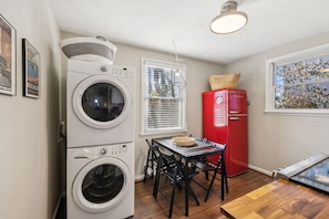 A compact kitchen with a washing machine, a red refrigerator, a dining table with chairs, and a window with blinds. - Family Friends and free parking 1mile to downtown (Nashville)