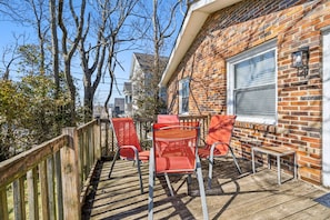 A wooden deck with outdoor seating, a brick wall, and a window.