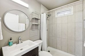 A bathroom with a sink, mirror, and shower.