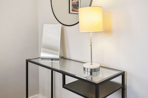 A modern glass table with a metallic base and a white cylindrical object on top.