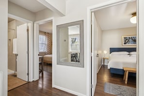 A bedroom with a bed, bedside tables, a mirror, and a window with blinds.