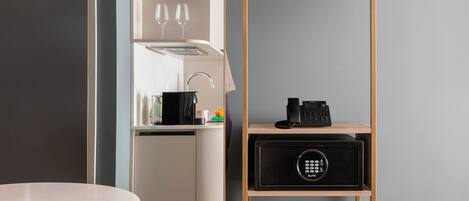 Una cocina moderna con horno empotrado, cafetera y teléfono negro en un estante.