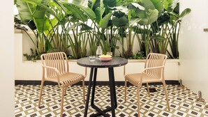 Une petite terrasse avec deux chaises, une table et un sol carrelé.