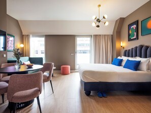A modern hotel room with a large bed, a dining area, and a view of the city. - Numa Lisbon Rato (Lisbon)