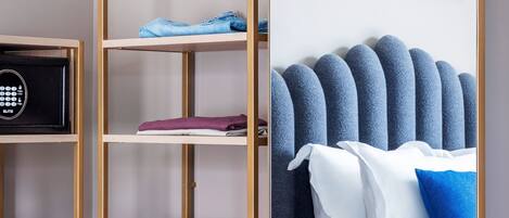 Une chambre d’hôtel comprenant un lit, une armoire avec des étagères, une valise et un coffre-fort.