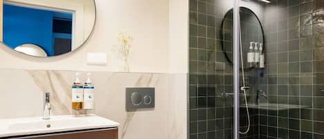 A modern bathroom with a glass-enclosed shower, a marble vanity, and a toilet.