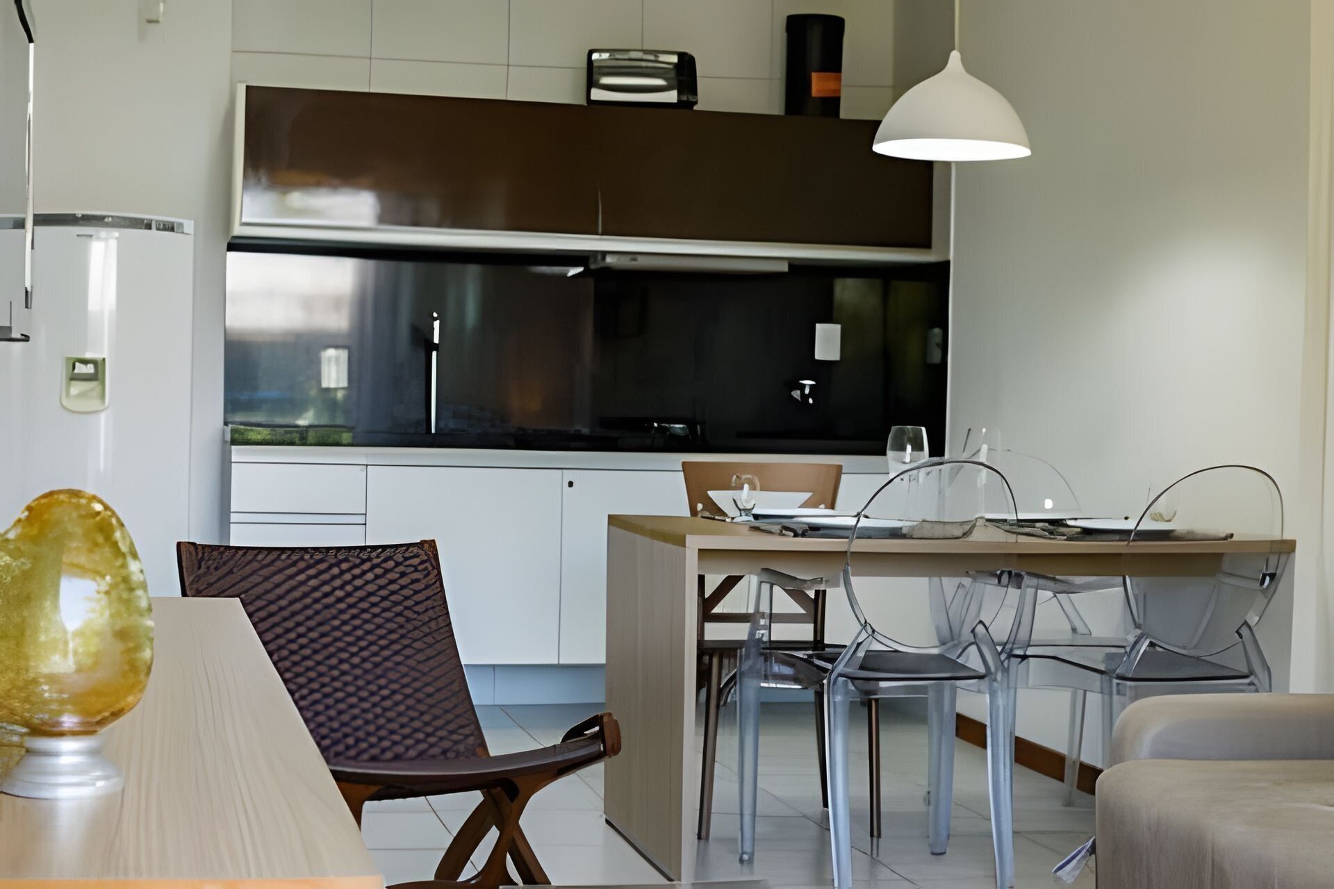 Eine moderne Küche mit weißen Schränken, einer schwarzen Arbeitsplatte und einem Essbereich mit Holztisch und Stühlen.