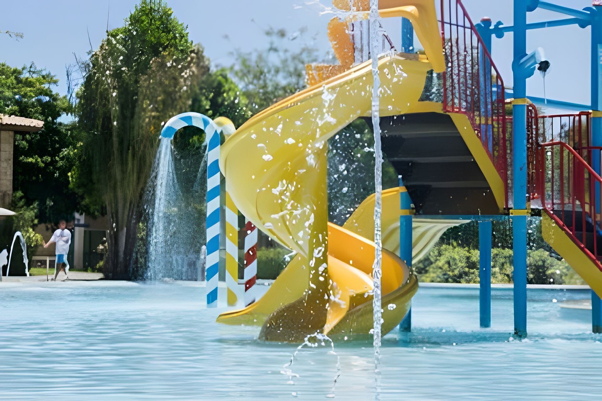 A water play area with a yellow slide and a blue and white striped tube slide.