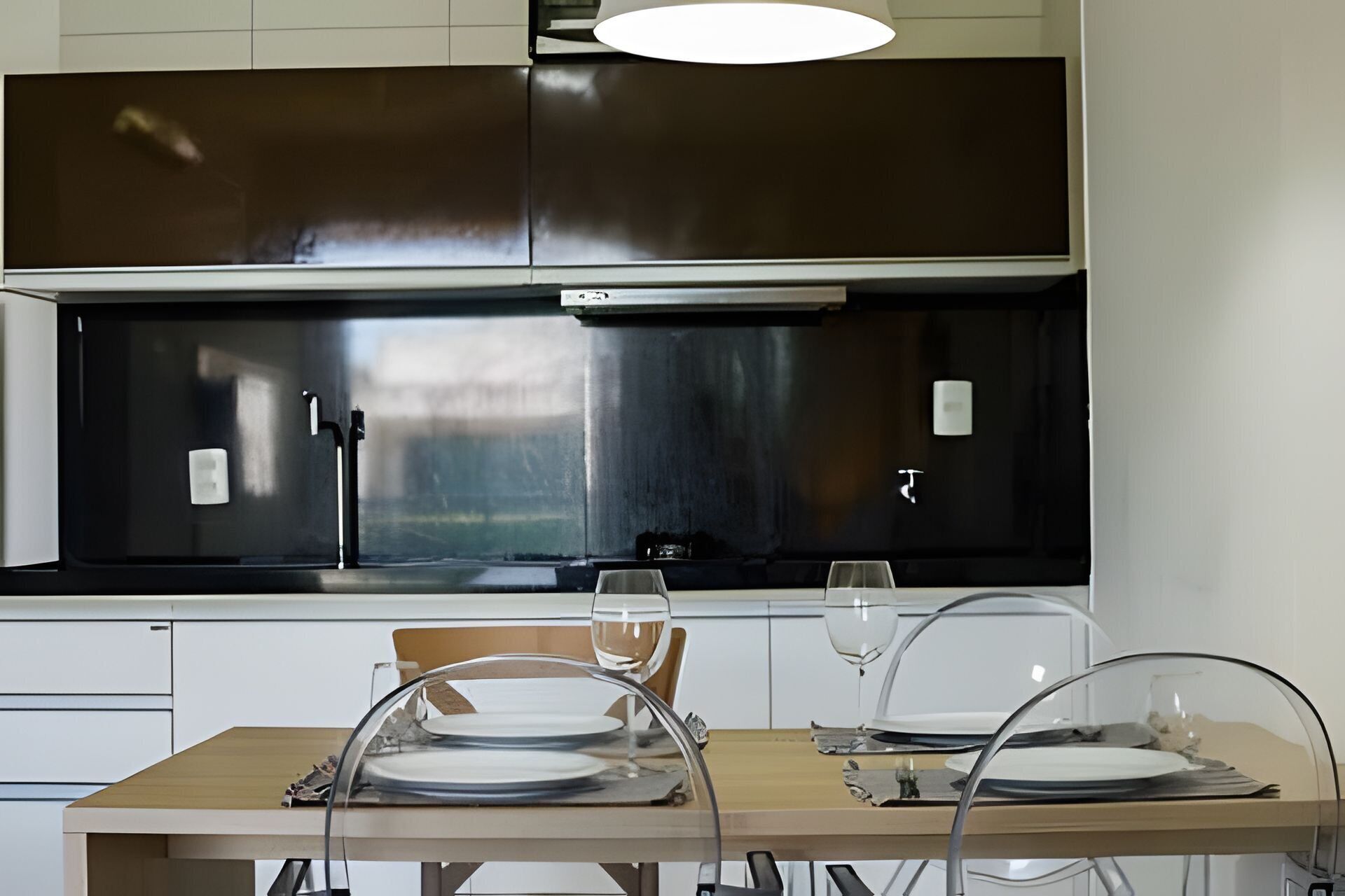 A modern kitchen with stainless steel appliances, a dining table with chairs, and a pendant light.