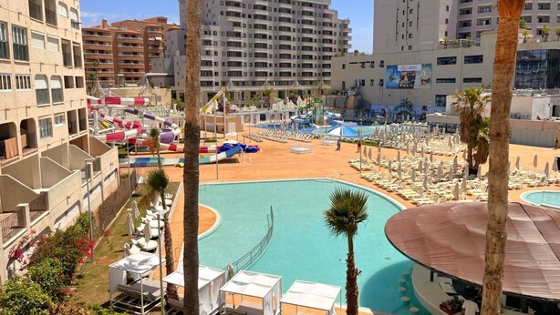 Ein Hotelpoolbereich mit mehreren Pools, Liegestühlen und einer Rutsche.
