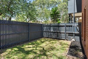A fenced backyard with grass and a tree. - Flora  Pet Friendly Coastal Hampton Retreat (Hampton)