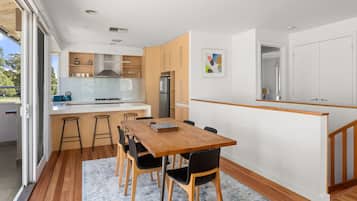 A modern kitchen with a central island, wooden cabinets, and a dining area with a table and chairs.