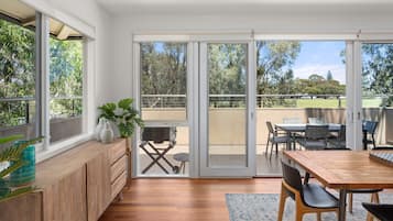A modern kitchen with a wooden countertop, a dining area with a table and chairs, and a sliding glass door leading to an outdoor patio.