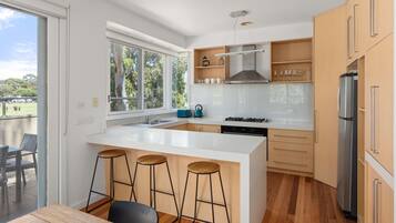 A modern kitchen with a large island, bar stools, a built-in oven, and a refrigerator.
