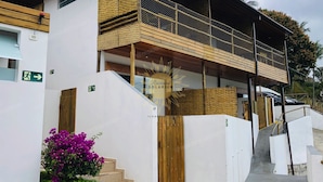 A modern building with a wooden balcony, a staircase, and a sign indicating an emergency exit. - Residencial Solariun Ilhabela (Ilhabela)