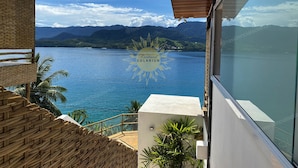 A view from a balcony overlooking a large body of water with mountains in the background. - Residencial Solariun Ilhabela (Ilhabela)