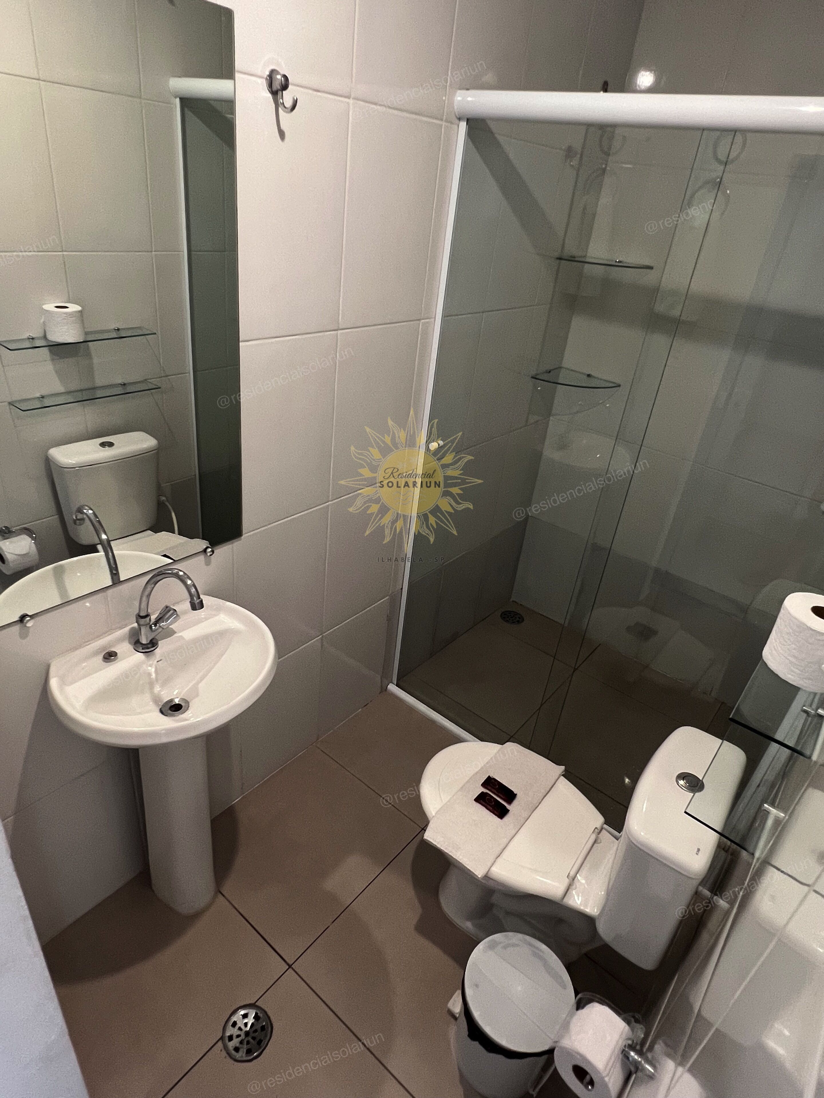 Uma casa de banho moderna com cabine de duche em vidro, lavatório suspenso e sanita.