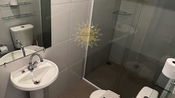 Uma casa de banho moderna com cabine de duche em vidro, lavatório suspenso e sanita.