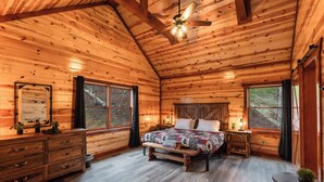 Une chambre dans une cabane en rondins, avec un lit, une commode et deux fenêtres.