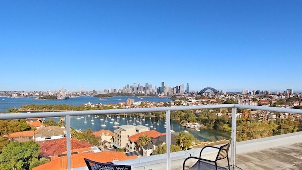 Uma varanda com vista para um porto de iates e o horizonte da cidade.