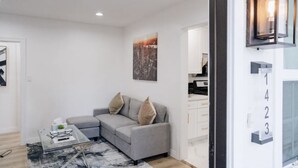 Ein modernes Wohnzimmer mit einem grauen Sofa, einem Glastisch und einem Stadtbild an der Wand.