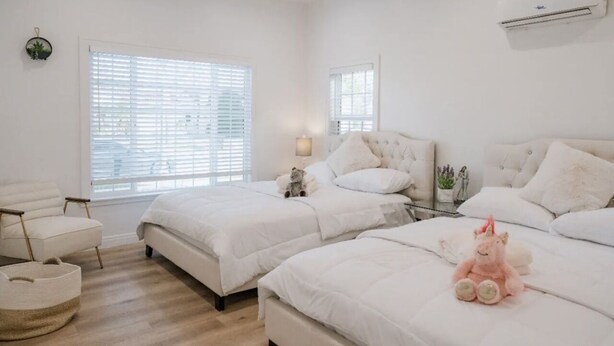 Ein Schlafzimmer mit zwei Betten, einem Sessel, einer Lampe und einer kleinen Pflanze.