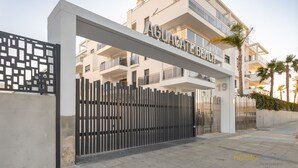 Un edificio de apartamentos moderno con entrada porticada, balcones y cielo despejado.