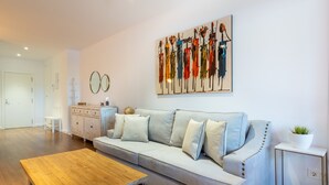 Un salon moderne avec un canapé gris, une table basse en bois et un tableau accroché au mur.