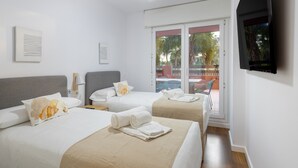 Une chambre d’hôtel avec deux lits, un ventilateur de plafond, une télévision et une porte-fenêtre coulissante donnant sur l’extérieur.