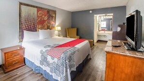 A hotel room with a bed, a desk, a television, a mirror, and a painting on the wall. - Hotel O Daylight Inn Elkhart I-90, In (Elkhart)